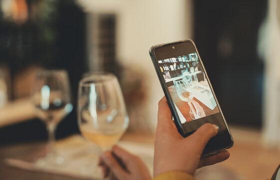 Woman takes a picture of glass of wine at tasting.