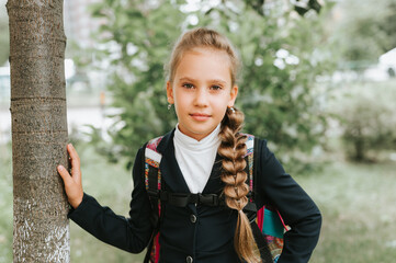 back to school. little happy kid pupil schoolgirl eight years old in fashion uniform with backpack...