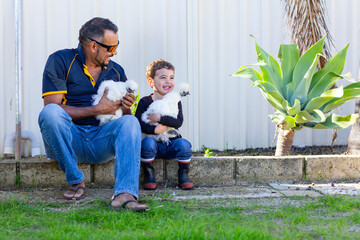Father and little boy holding silky bantams in back yard