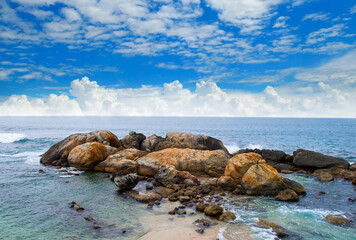 Fototapeta na wymiar Landscape with beach, sea, picturesque boulders and beautiful clouds in the blue sky.