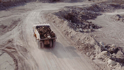 Dump truck loaded with ore and driving through the pit. Big yellow heavy truck in open cast mine mining of coal the overall plan. Open pit anthracite mining, mining truck at work working in quarry © uflypro