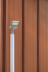Modern LED solar power street light post against wooden trellis wall outside of vintage building in vertical frame