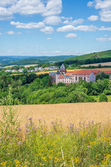 Fototapeta na wymiar St. Wendel, Saarland, Deutschland – Blick auf das Missionshaus mit Kirche und die Landschaft des Sankt Wendler Lands im Sommer