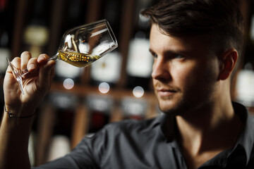 Bokal of white wine on background, male sommelier appreciating drink