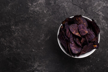 Purple sweet potato chips on black stone background