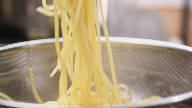 Stirring boiled spaghetti with olive oil.
