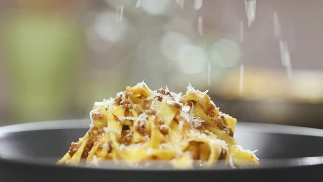 Chef grating parmesan on classic Tagliatelle al Ragu Bolognese.
