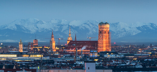 Munich skyline night view downtown cathedral church frauenkirche in background alps mountins winter snow.
