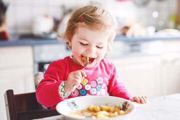 Adorable baby girl eating from fork vegetables and pasta. food, child, feeding and development...