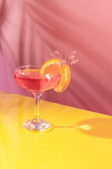 Glass of delicious alcoholic cocktail with rose water and sparkling wine isolated over pink yellow background