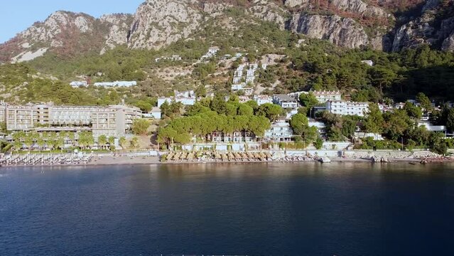 Panoramic drone view of seaside and beach in resort village Turunc in Turkey. Resort embankment view from sea. Touristic resort town surrounded by mountains