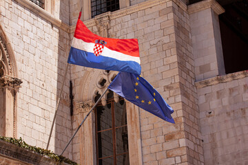 Croatian and EU European Union flags waving from building in old town of Dubrovnik. Croatia is the youngest country that joined the European Union in 2013. - obrazy, fototapety, plakaty
