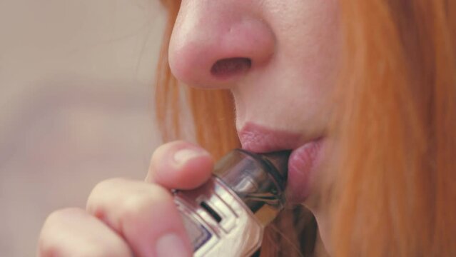 close up portrait of young woman intending to quit smoking uses electronic cigarette
