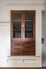 Antique wood cabinet in the farmhouse. Dark brown rustic interior furniture against a white wall.
