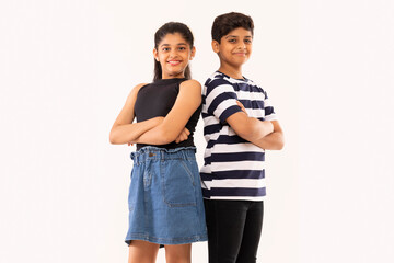 Cheerful boy and girl standing back to back with crossed arms