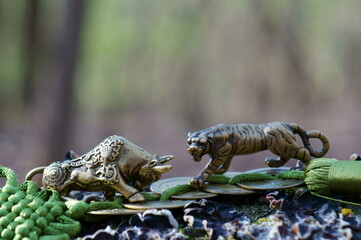 A bull figurine and a bunch of Chinese coins in close-up.  Next to the figure of a tiger. A religious symbol.