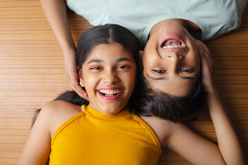 Close-up of boy and girl lying down on wooden floor  - Powered by Adobe