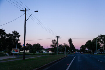 Fire danger rating sign and silhouettes of power poles and light posts beside road in country town