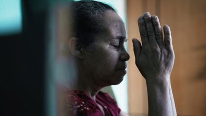 Contemplative South American senior woman praying. One spiritual older lady at home