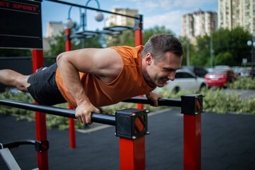 Fototapeta na wymiar Strong Sport Man Is Training Outdoor City. Young man doing push-ups during outdoor cross training workout.