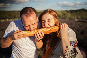 Couple on romantic picnic with french baguette in lavender field. Vacation and travel concept.  