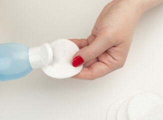 Young woman pours nail polish remover onto a cotton pad.
