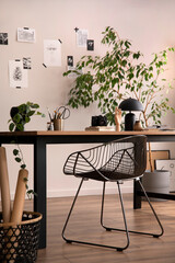 The stylish composition of cozy office interior with metal chair, wooden table, plants poster and personal accessories. Home decor. Template.