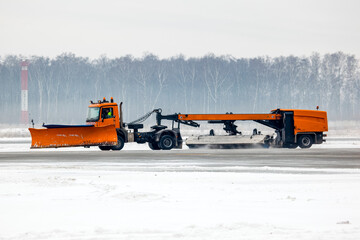 Snowplow truck cleans runway on airfield during snowfall