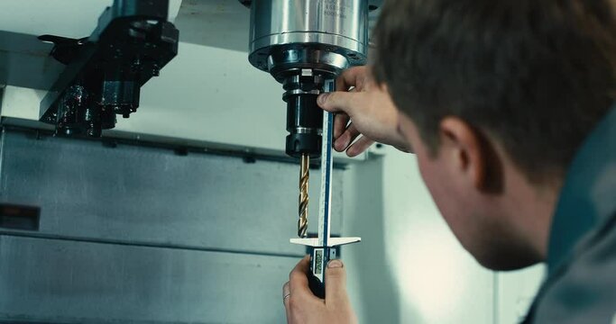 a man adjusts a cnc machine with a drill. Modern industry.