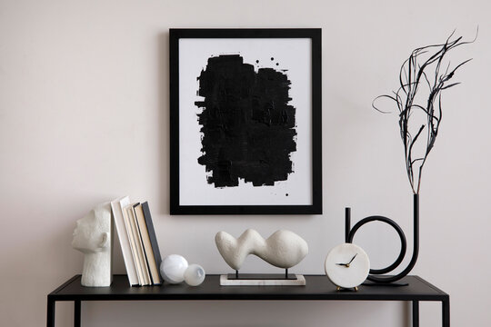 The stylish composition of minimalistic interior with mock up.  Black commode, vase with dried flowers, sculptures and personal accessories. Beige wall. Mock up poster. Template.