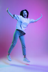Fototapeta na wymiar Adorable excited girl, young woman with long glossy dark hair isolated on purple background in neon light. Concept of beauty, art, fashion, emotions