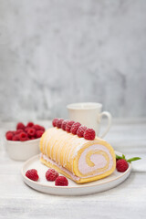 Tasty roll cake, sponge roll, Swiss roll  stuffed with cream cheese ,decorated with fresh raspberries.  