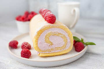 Tasty roll cake, sponge roll, Swiss roll  stuffed with cream cheese ,decorated with fresh raspberries.  