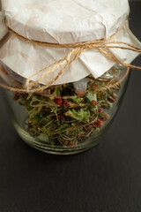 glass jar filled with dried wild strawberries closed with piece of craft paper and tied with twine