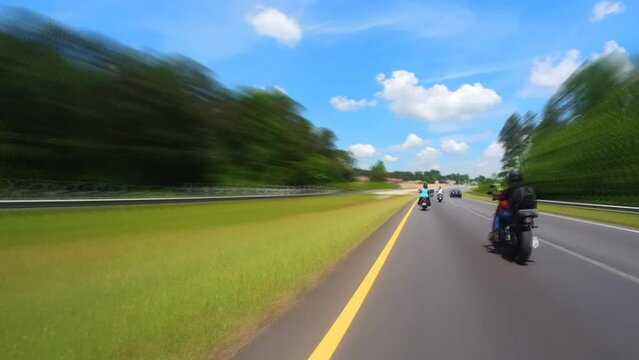 Women riding motorcycles in a group on a country road on a sunny day with a clear blue sky