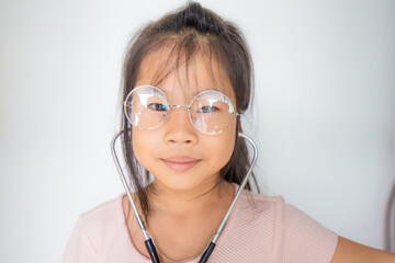 Adorable glasses child girl playing with doctor costume with sthetoscope