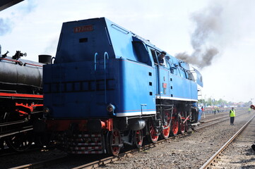 Retro historical antique steam locomotive running on rail tracks and puffing with smoke and steam in Wolsztyn, Poland, Europe