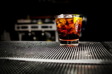 glass of iced cocktail on bar background. Wiskey in glass with light on black background. Glass of...