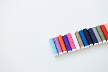 Color sewing threads on white background, top view