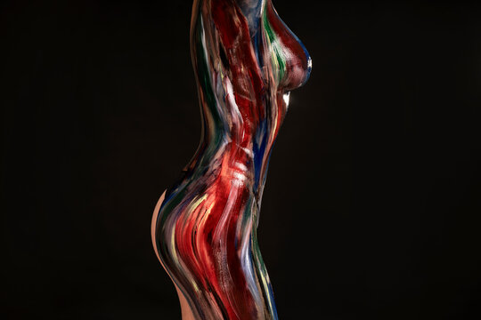 Body part art. Photo of female sensual creative body in colorful paints on a black studio background.