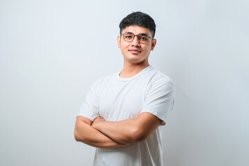 Portrait of young handsome Asian man wearing casual shirt and glasses standing with arms crossed...