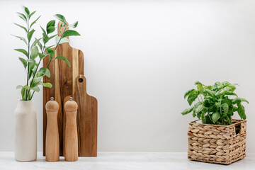 Wooden cutting board, kitchenware and plant in basket