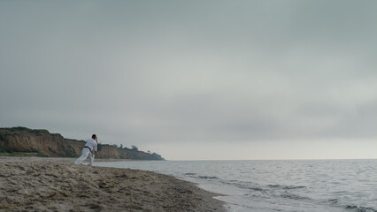 Professional karate man training on sandy beach. Athlete practicing taekwondo.