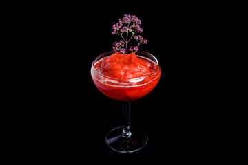 Red cocktail on the black background. With flowers and sorbet.