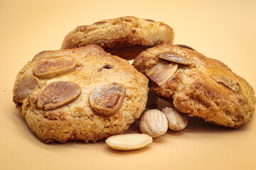homemade sweet almond cookies biscuits (amaretti) isolated on orange with three almonds