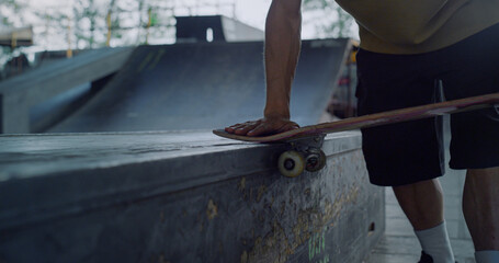 Man hands touching skateboard wheels at skate park. Riding skate board wheel. 