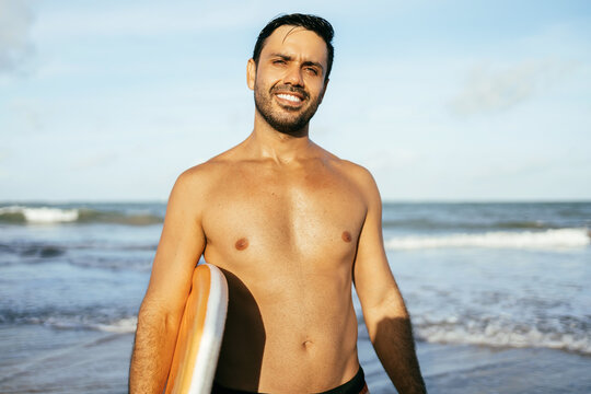 Portrait of Brazilian surfer standing at the beach with his bodyboard. Sport and water sport concept.