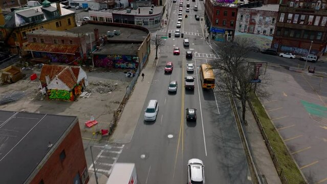 Forwards Tracking Of Yellow School Bus Driving Through Streets Of Urban Neighbourhood. Heavy Traffic In City. Boston, USA