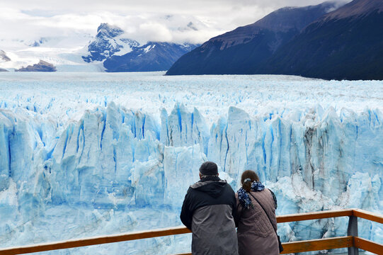 Pareja en Glaciar Perito Moreno, El Calafate, Patagonia Argentina. Glaciers in the water near snowy mountains