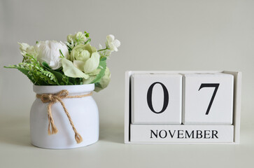 November 7, Cover natural background, white wooden Calendar cube with a pot flower on white background.